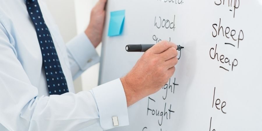 Hombre escribiendo en Pizarra las diferencias entre exámenes por nivel de Cambridge